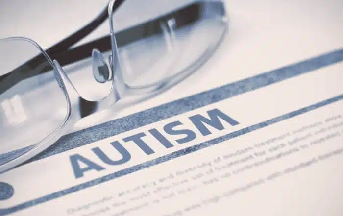 autism written on the white paper with the glasses on it