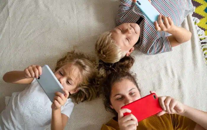 Kids lying on the floor and playing games on their phones