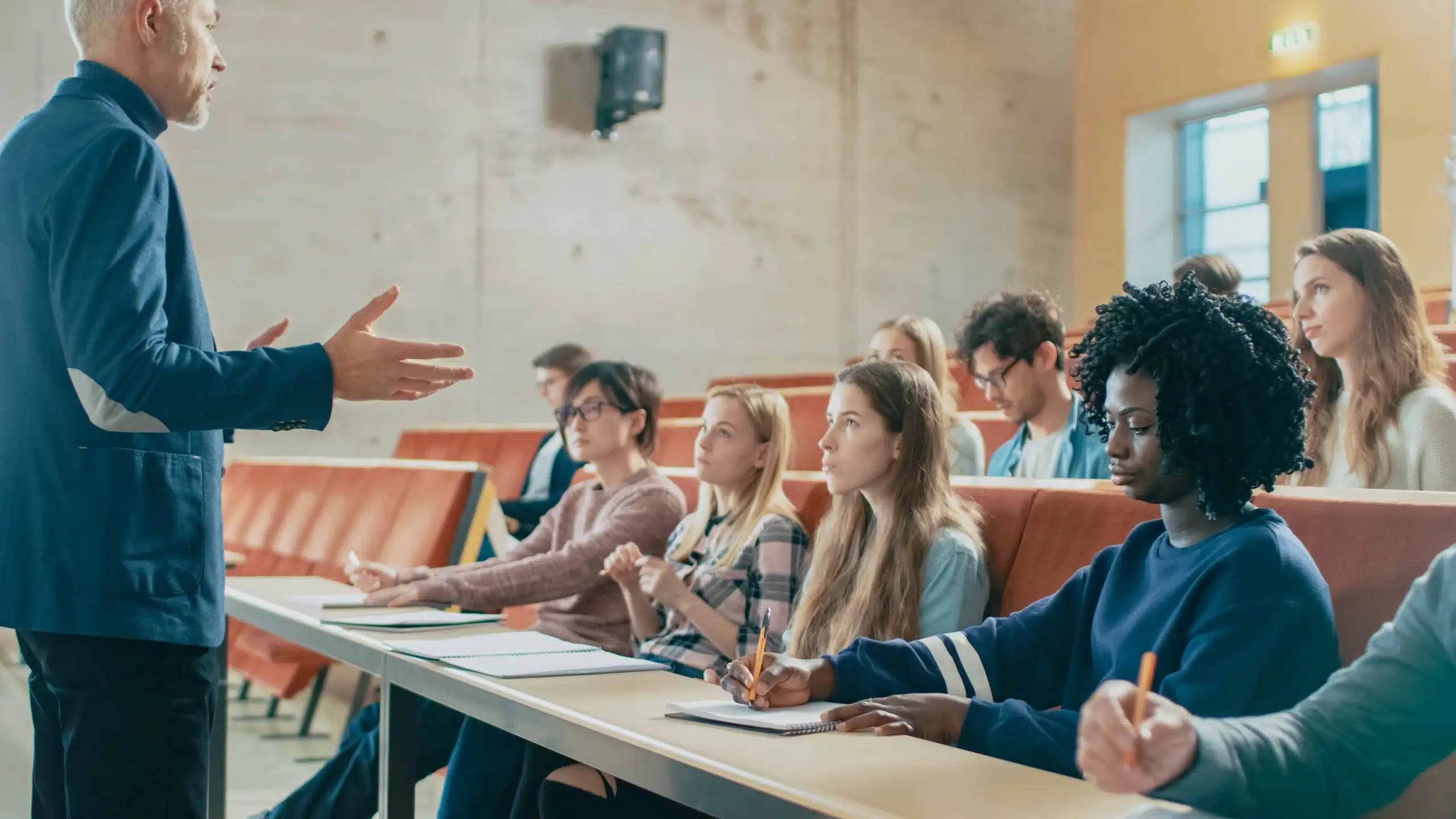 Professor standing and reading a lecture to a group of students