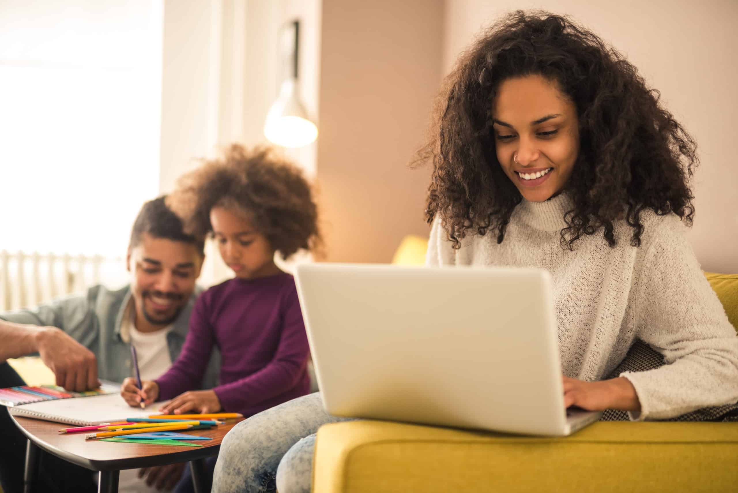 Father and child coloring together while mom works on her laptop