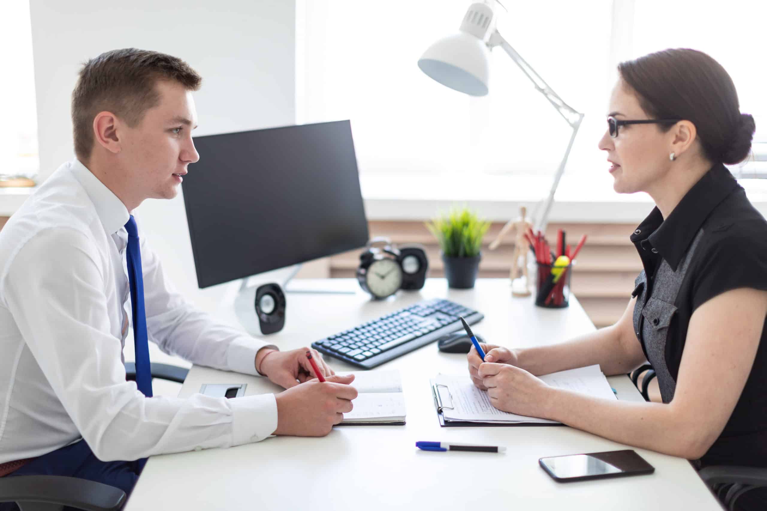 young man and women having a conversation over a desk at work Young man and women having a conversation over a desk at work