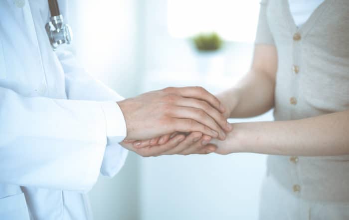 Hand of doctor reassuring her female patient. Medicine and health care concept