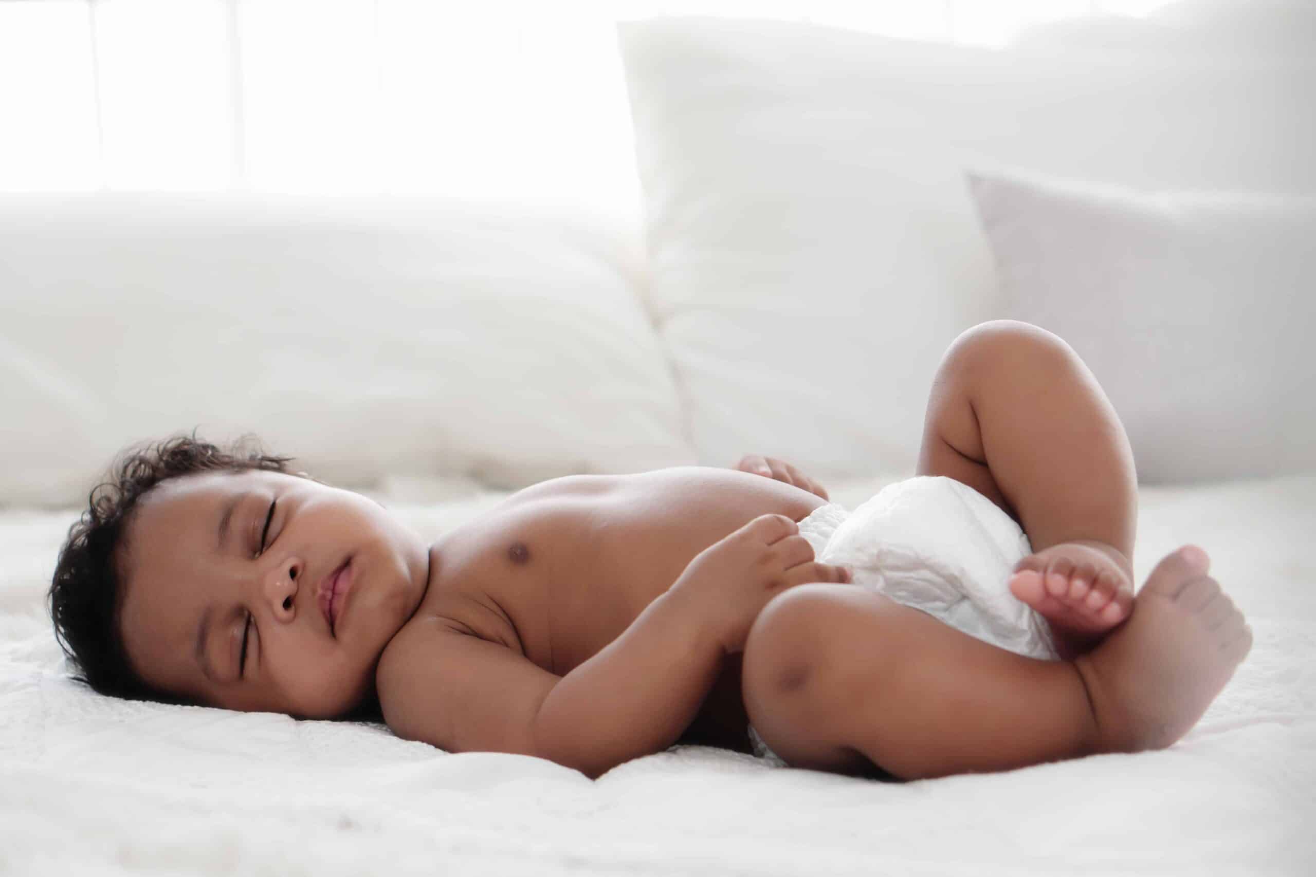 portrait of african american baby girl sleeping on white bed Close-up of a baby sleeping comfortably on a white bed