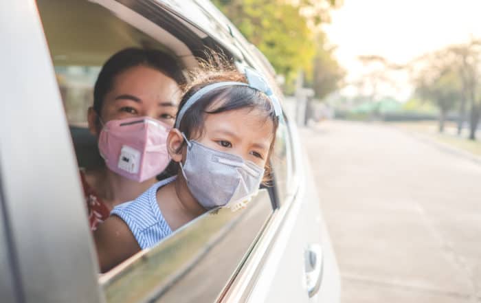 Mother and daughter wearing masks while sitting in the car
