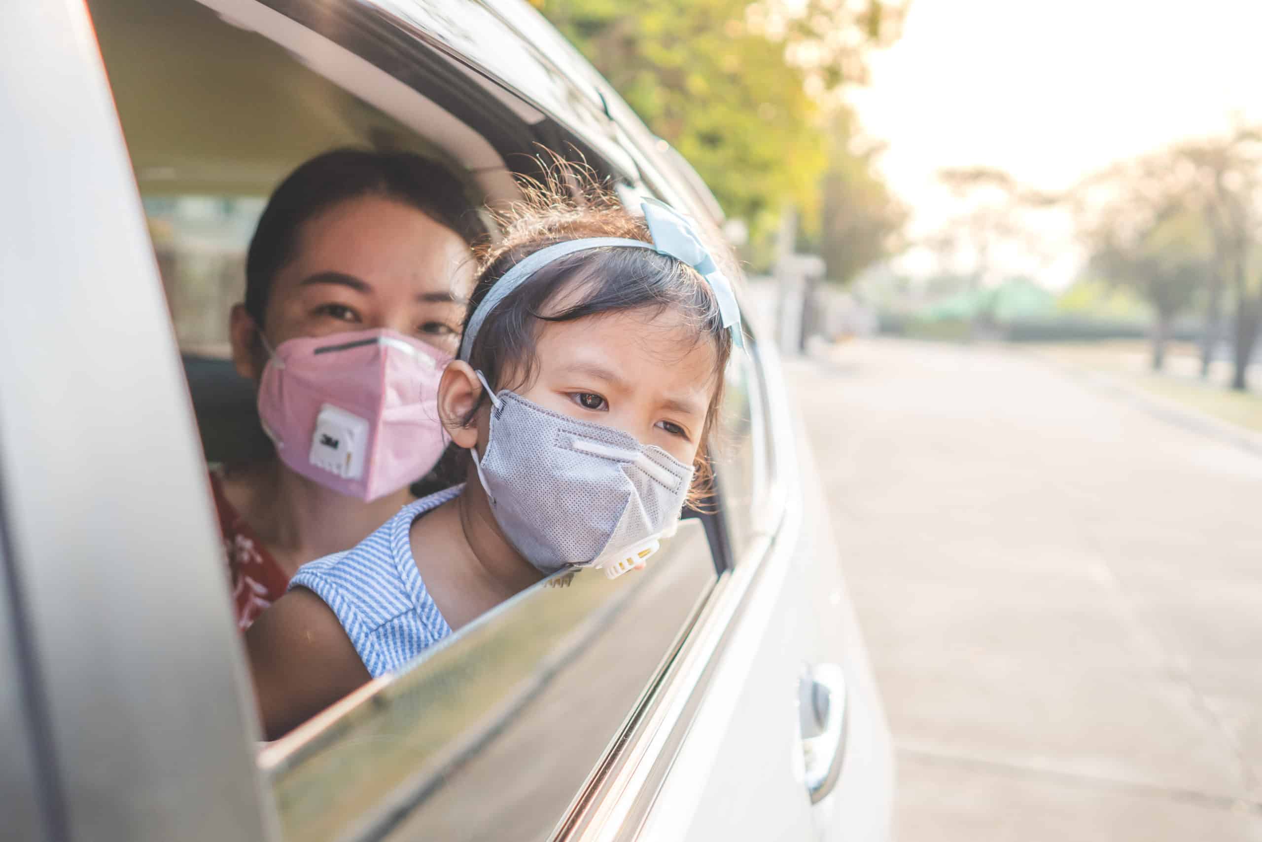 Mother and daughter wearing masks while sitting in the car