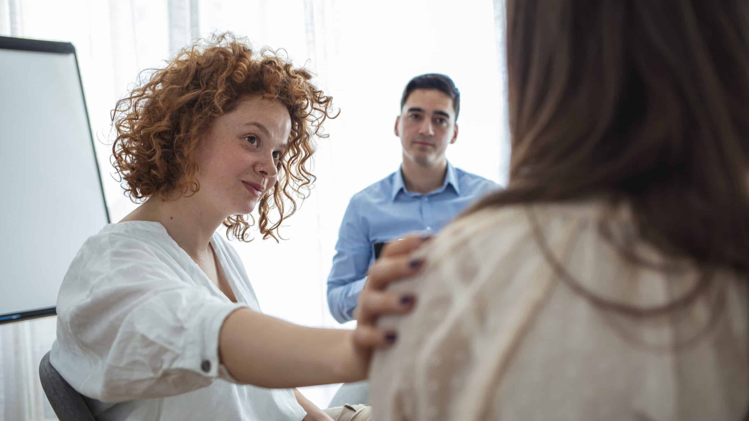 Support gesture. Woman comforting woman patient at group rehub meeting.