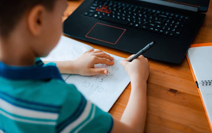 A schoolboy boy studies at home and does school homework.