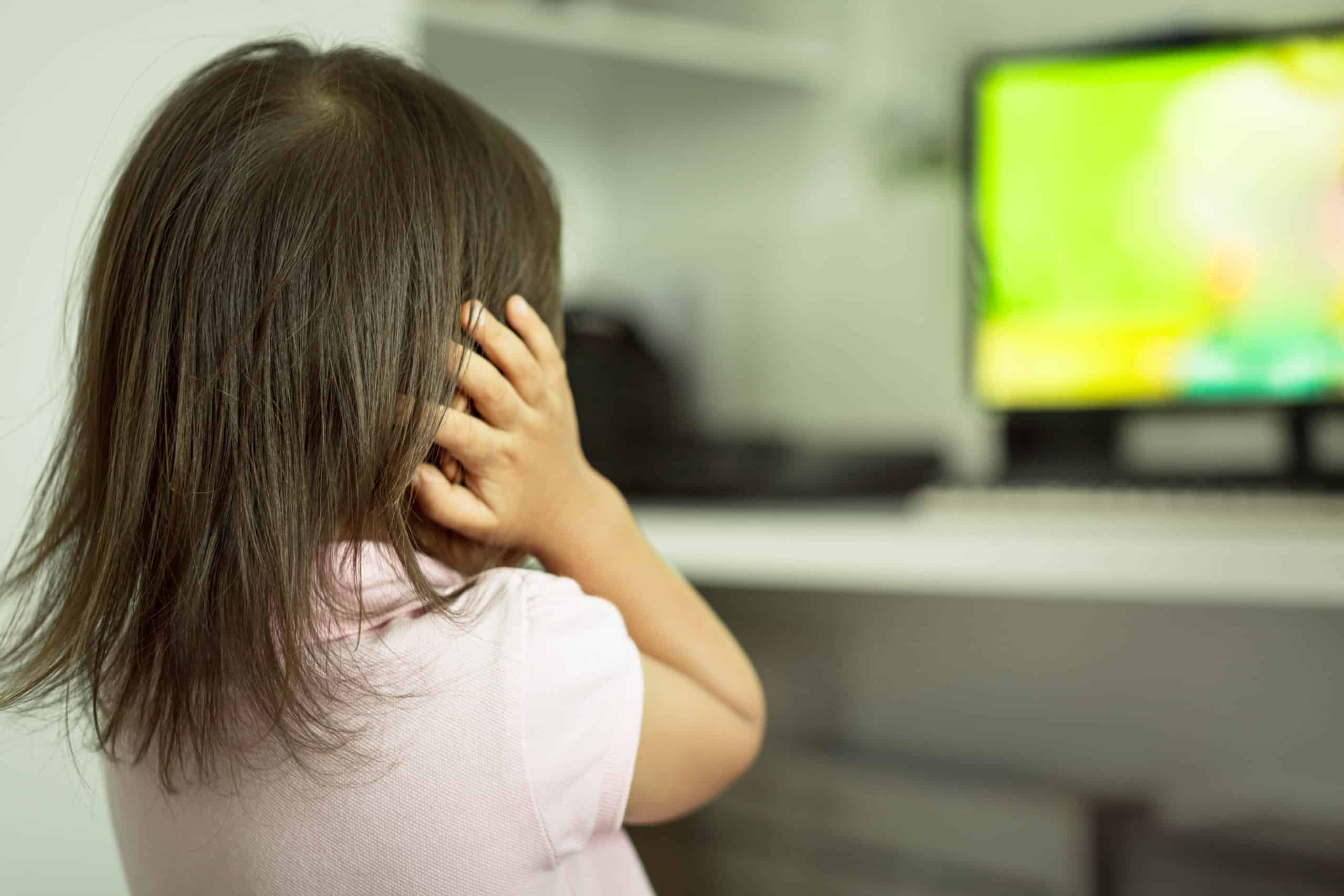 Sensitive kids afraid of loud sounds noise, in front of the tv covering ears in fear.