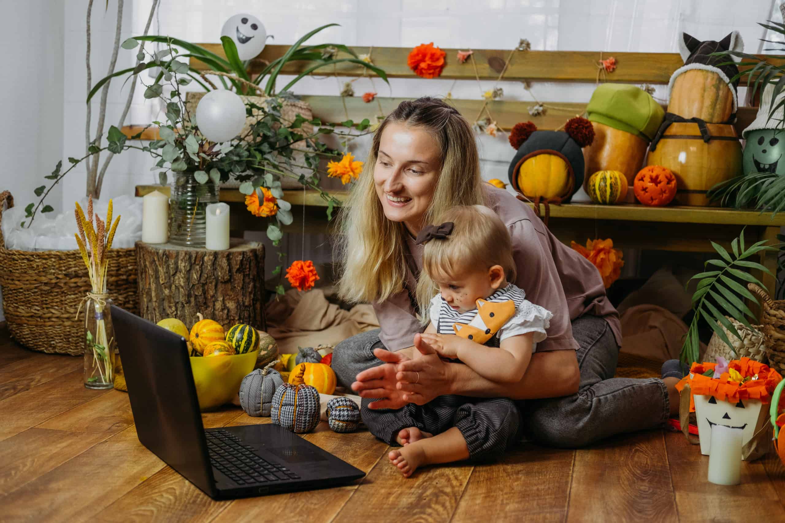 Holidays in the Time of COVID. Happy family, mother and baby celebrating Halloween via internet in new normal, Pandemic time. Online Holiday party concept.