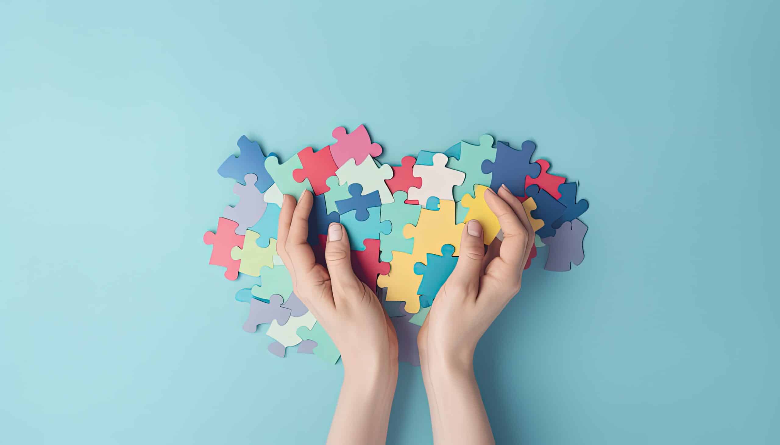 Hands holding a variety of colorful puzzle pieces