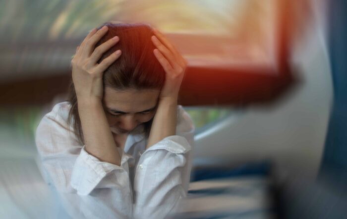 Close-up of a woman with her hands on her head, showing signs of anxiety