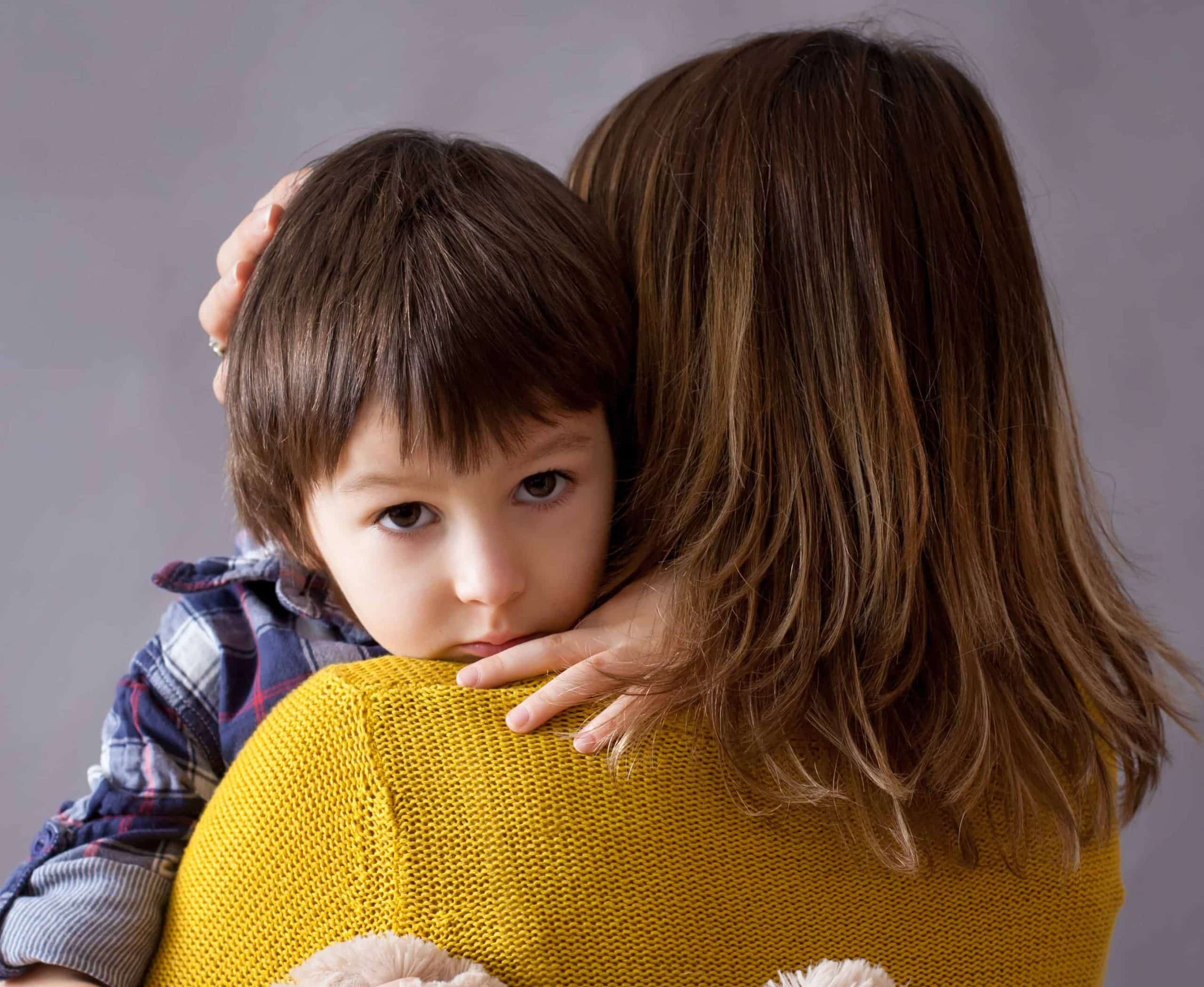 Sad little child, boy, hugging his mother at home, isolated image, copy space. Family concept