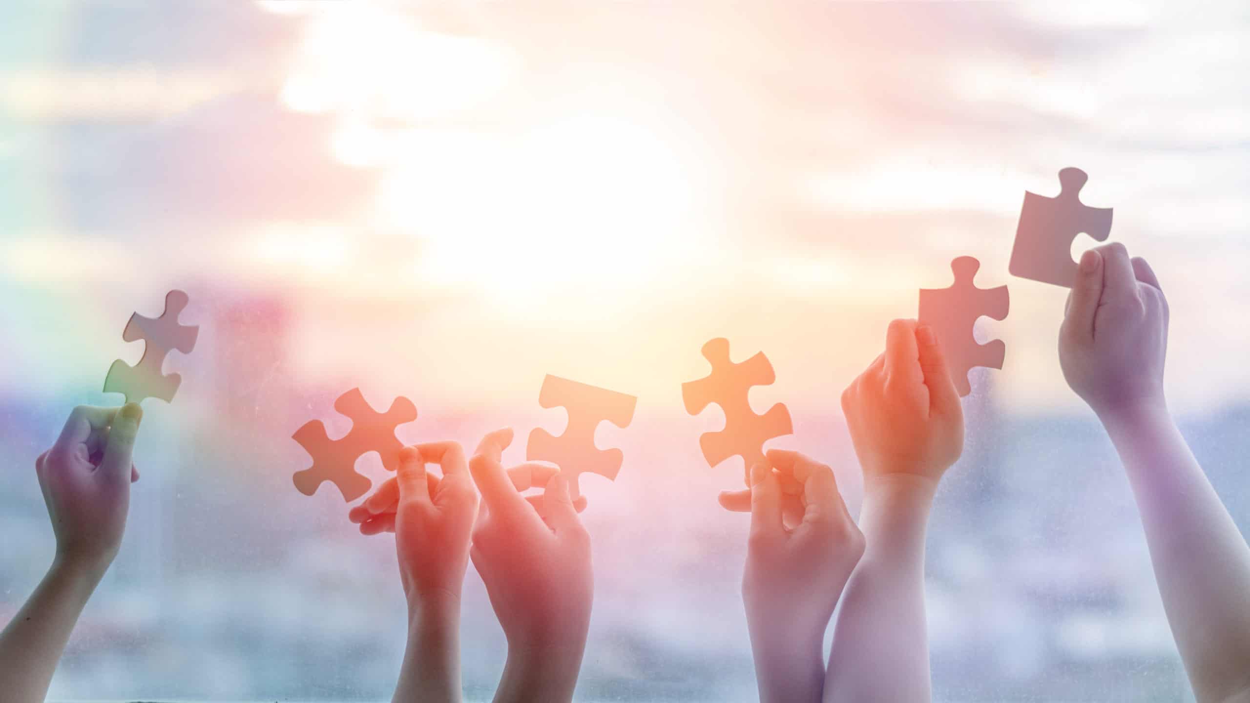 Hands of children students holding pieaces of puzzle together as a symbol for autism or teamwork in school.