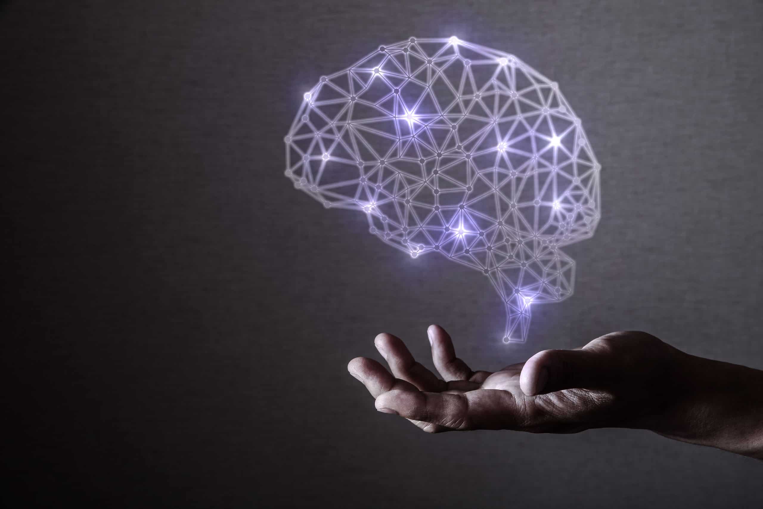 Hand held out and open below image of brain. Brain is lit up purple with lines of connection between different areas.
