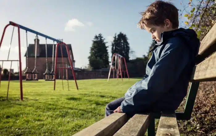 Upset child sitting alone on a playground bench