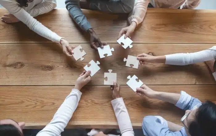 Close-up of a group of people holding puzzle pieces in their hands