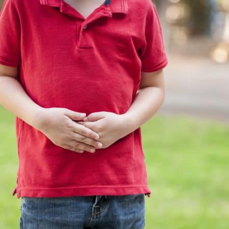Child holding their stomach, showing signs of gut distress