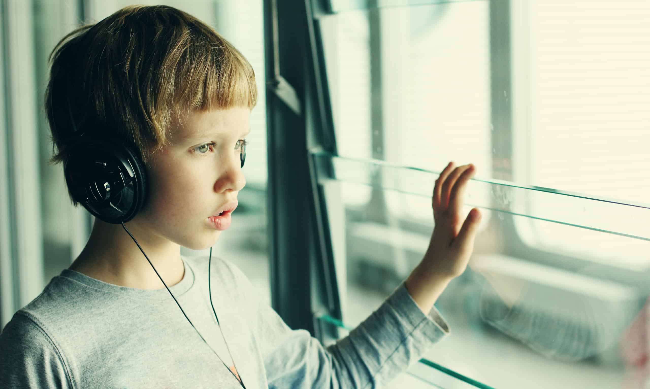 Young boy wearing headphones, looking out the window