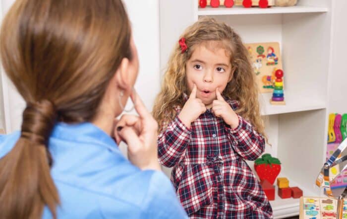 Young girl in speech therapy office. Preschooler exercising correct mouth form for sounds