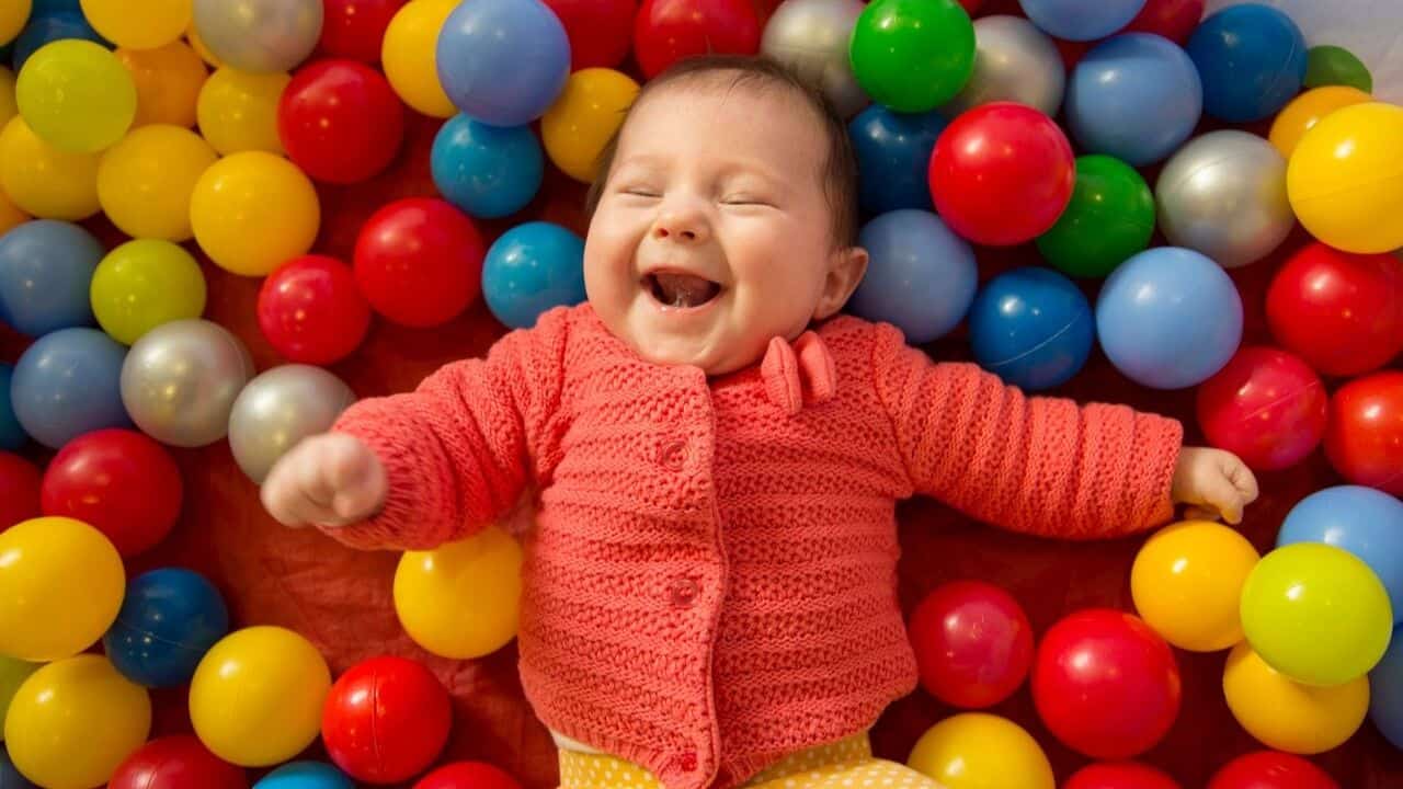 Baby lying on a bed surrounded by colorful balls