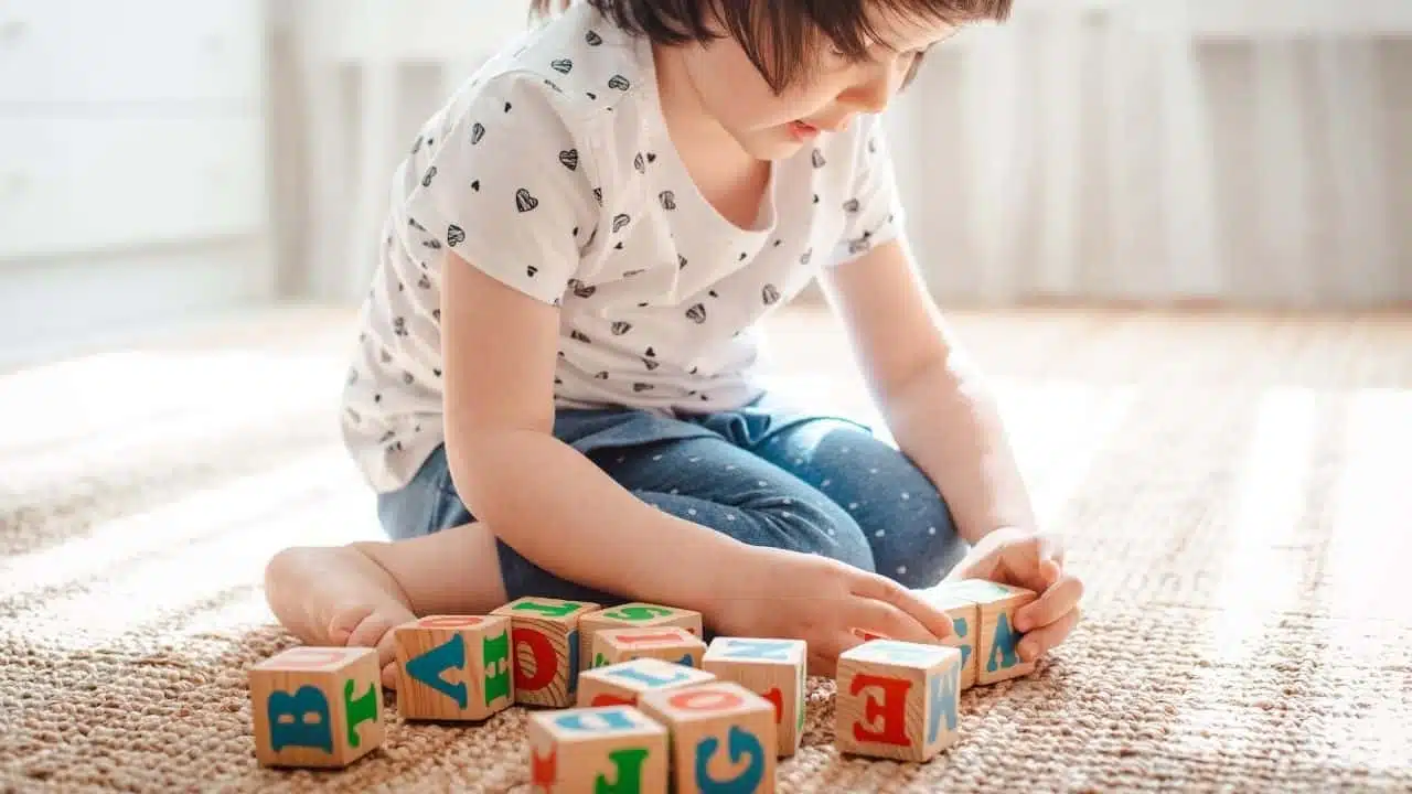 Child playing with alphabet cubes, forming words