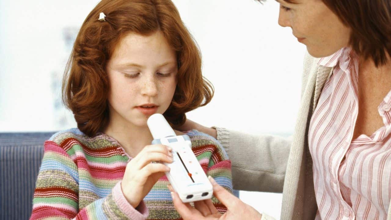 Mom helping her child use a peak flow meter