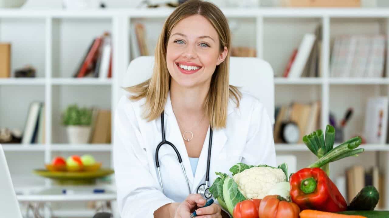Medical professional with a smile, vegetables placed in front