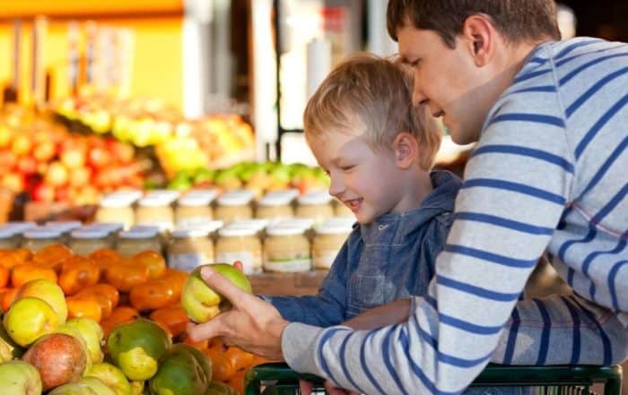 Dad and child selecting fresh fruit at the market