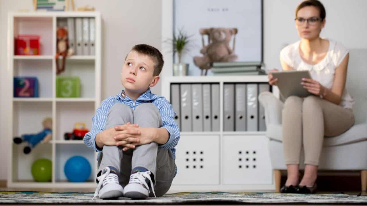 autism assessment Young child sitting quietly on the floor during a therapy session