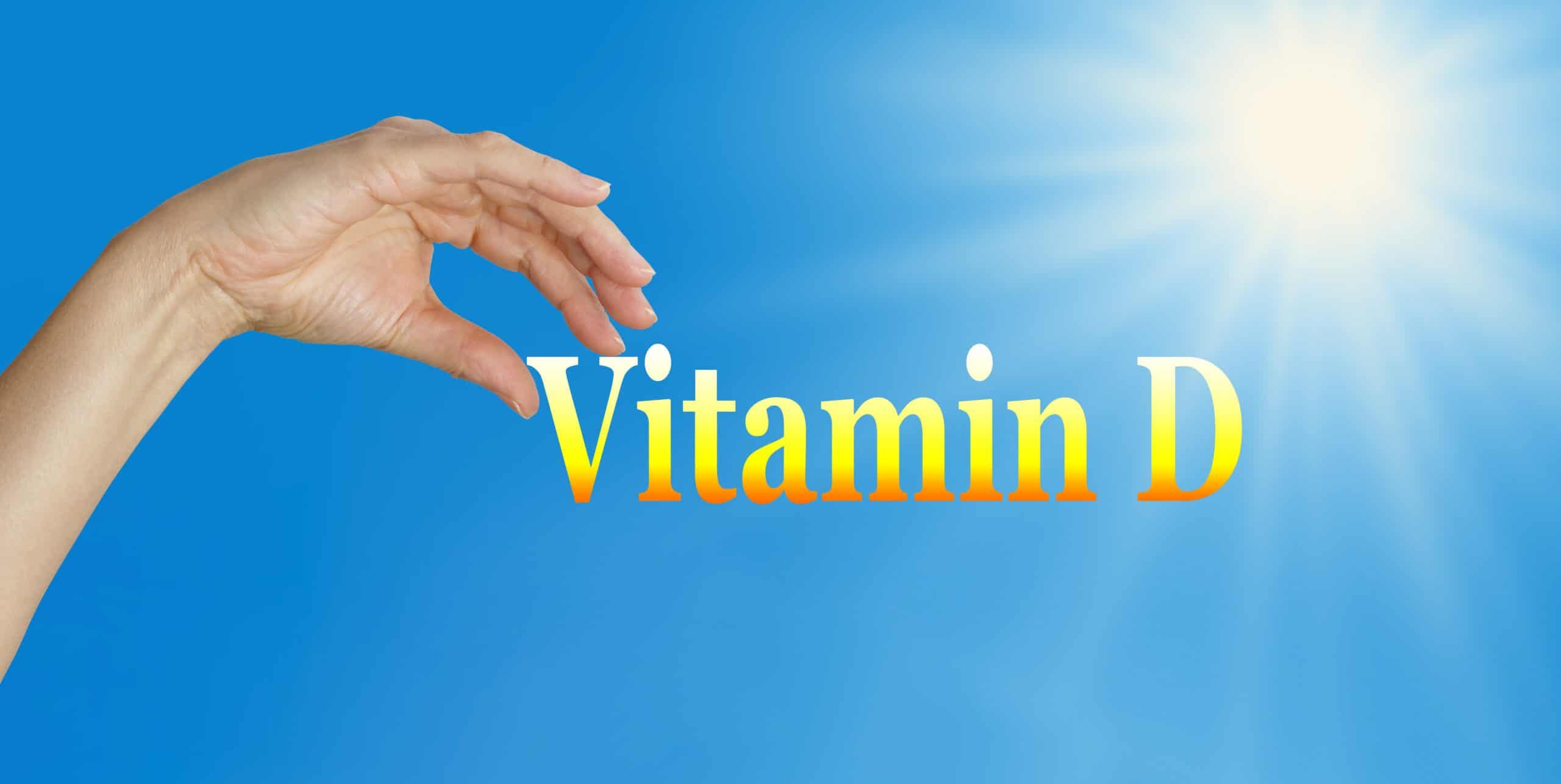 Sunshine and blue sky background with the word Vitamin D and a female hand poised to pick the D with plenty of copy space below