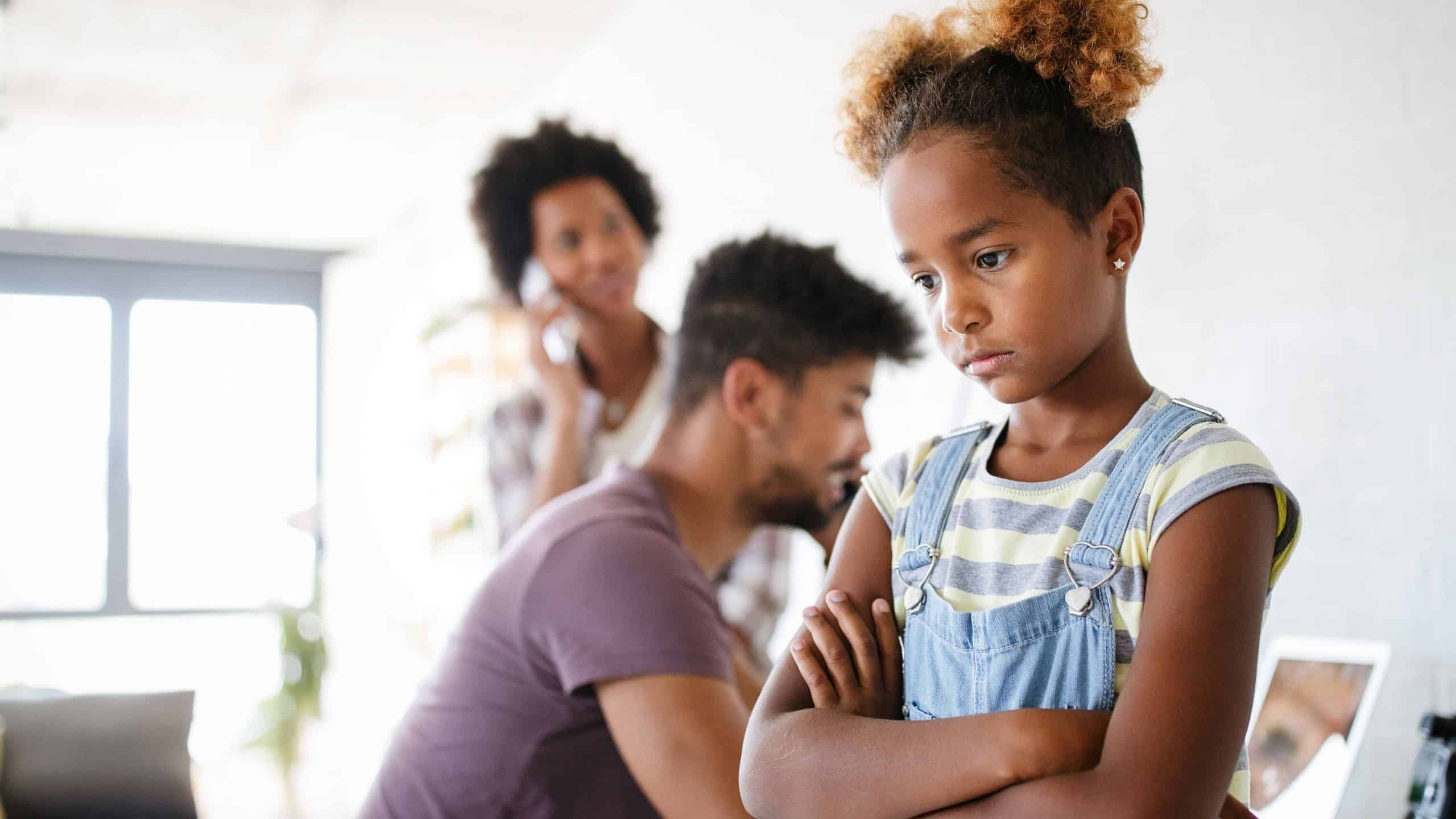 Sad child standing while both parents are talking on the phone