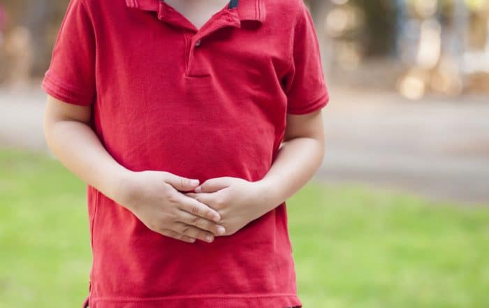 Young child dealing with gut problems, holding their stomach