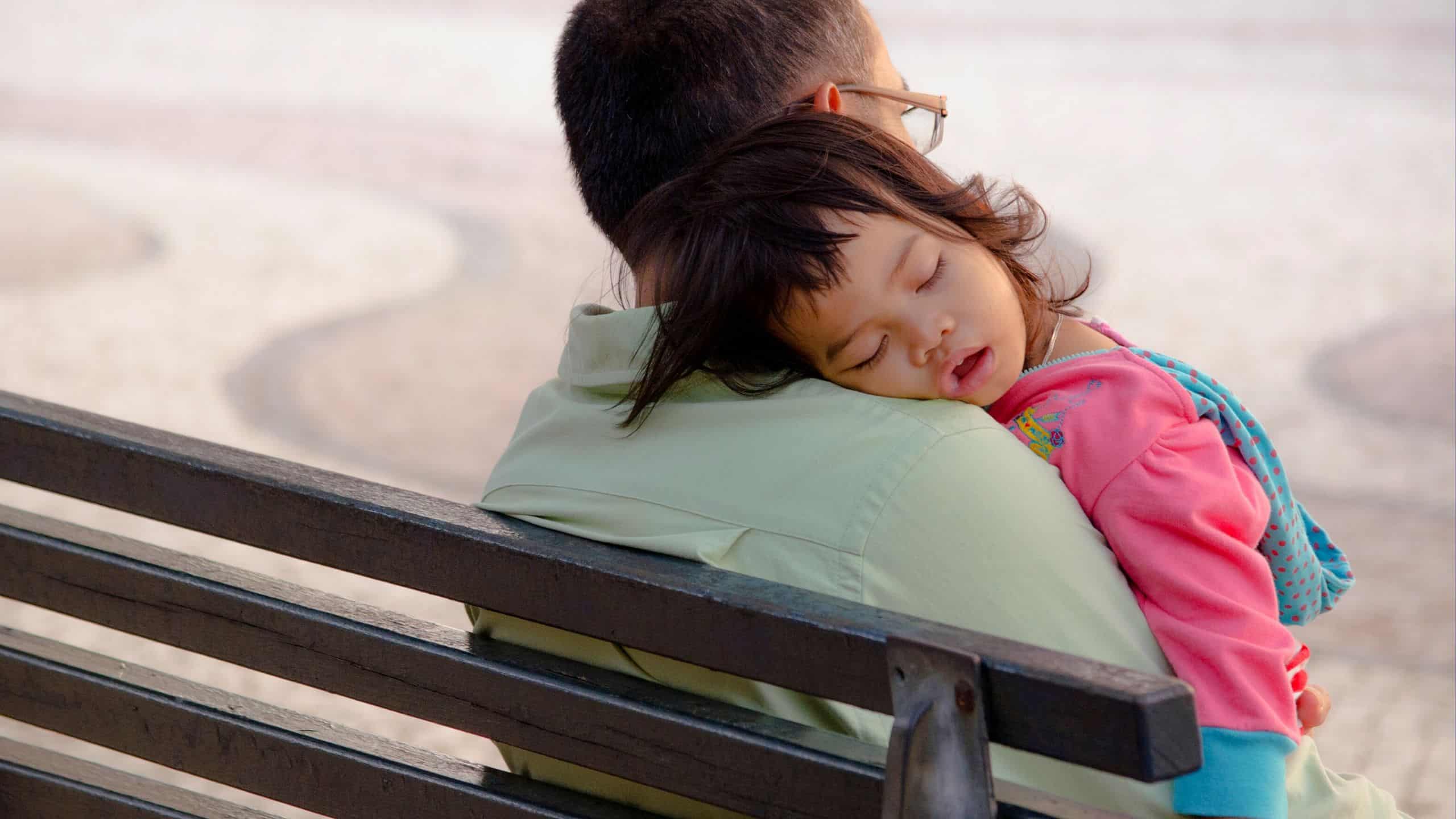 Child with autism peacefully sleeping on her father's shoulder