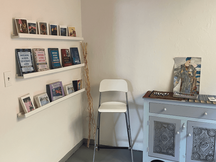 Interior of a white room featuring bookshelves, a light blue drawer with artwork, and a white chair